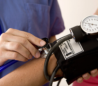 Doctor checking a patient's blood pressure during a chronic care visit
